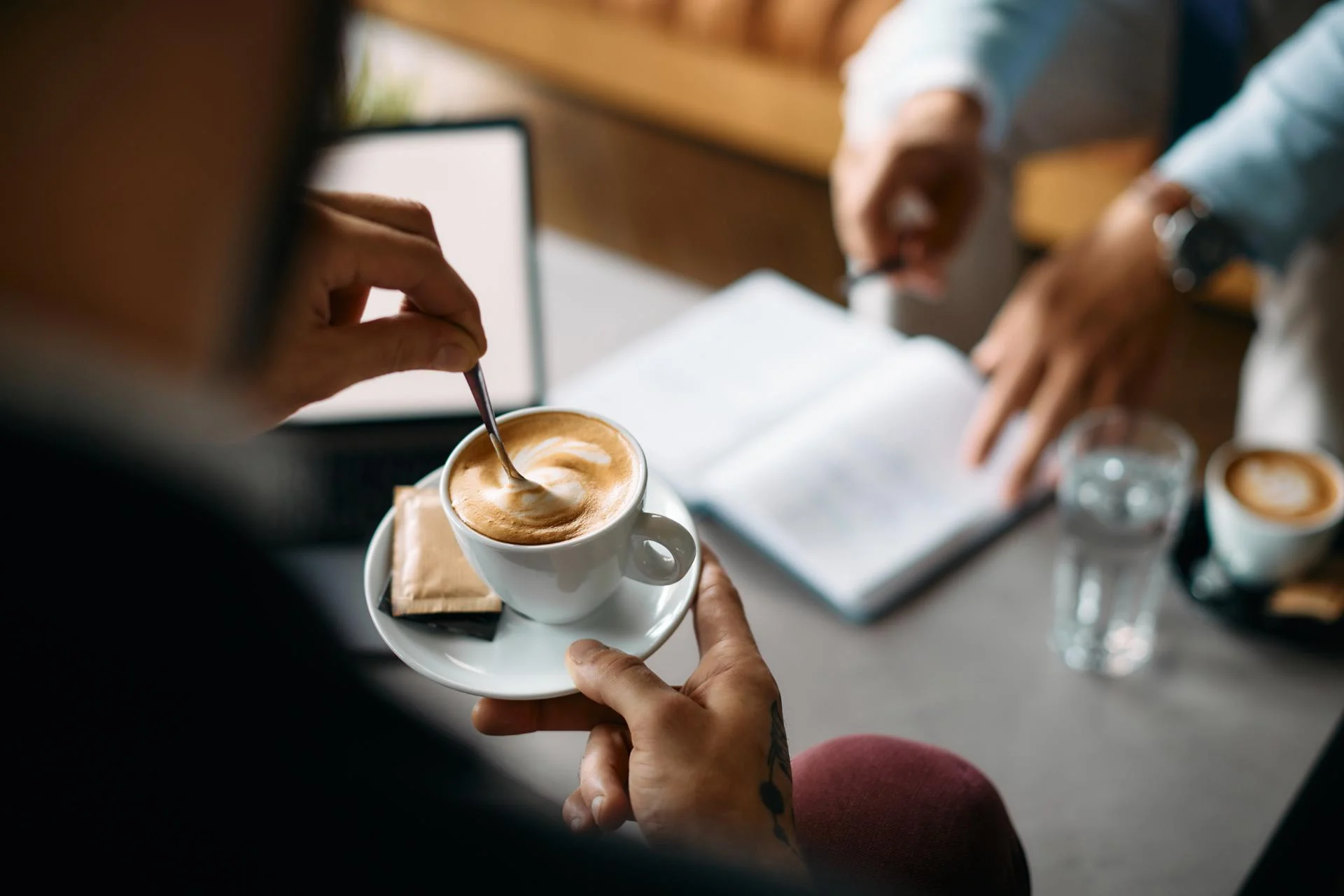 Two people talking over coffee with an open notebook